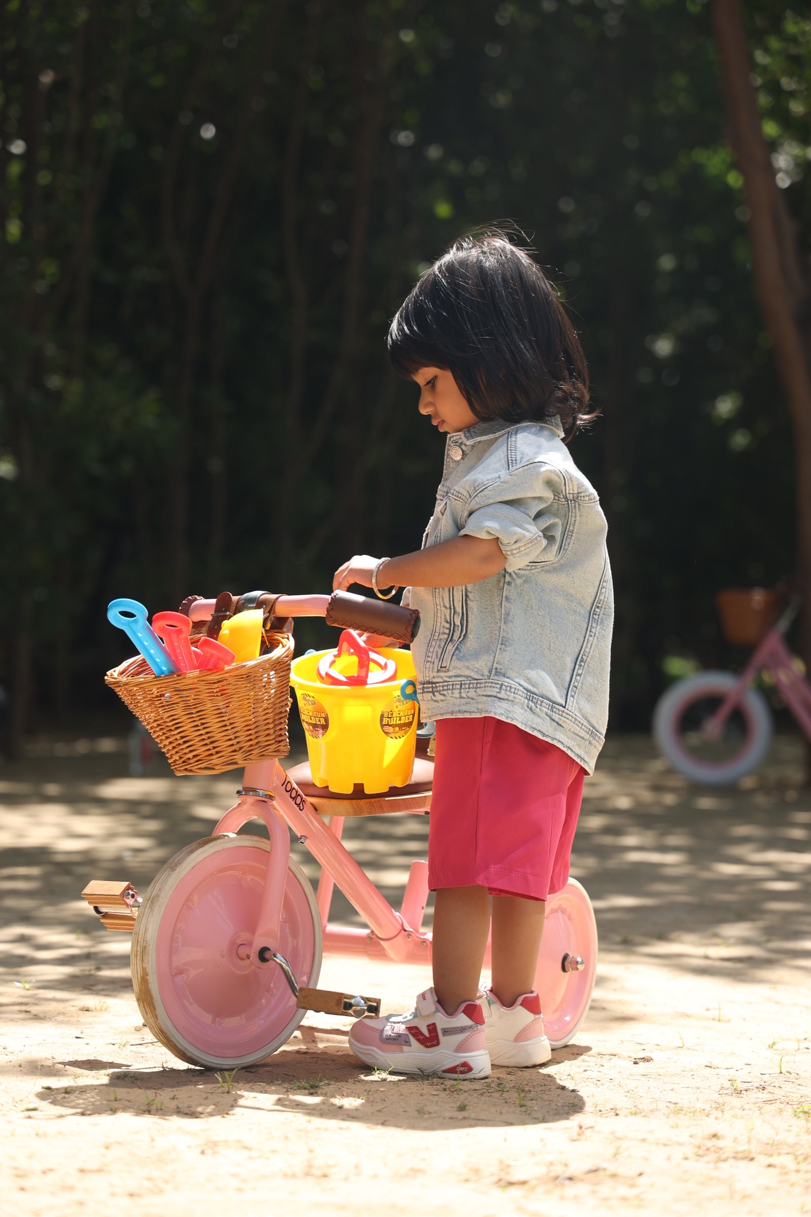 toddler with pink tricycle